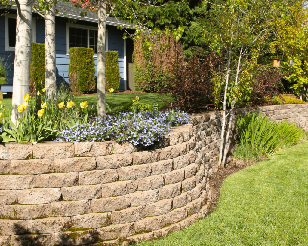 Image of an elegant stone wall providing structure and privacy in a garden, exemplifying the walls and fences services offered by Custom Creations in Marshfield, MO