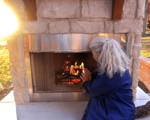 One of our clients warms herself up by her new outdoor fireplace.